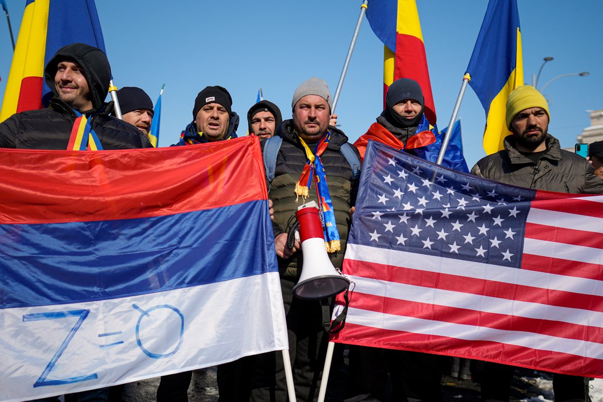 Сторонники Кэлина Джорджеску держат перевёрнутый российский флаг и флаг США на митинге после аннулирования первого тура президентских выборов Конституционным судом, Бухарест, 21 февраля 2025 года. Фото: Vadim Ghirda / AP Photo / Scanpix / LETA