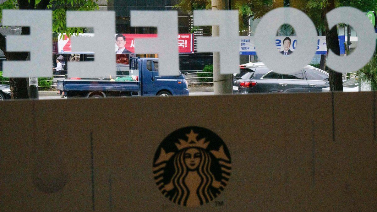 Предвыборные баннеры с кандидатами на пост президента на фоне вывески сети кофеен Starbucks в Сеуле, 15 мая 2025 года. Фото: Anthony Wallace / AFP / Scanpix / LETA