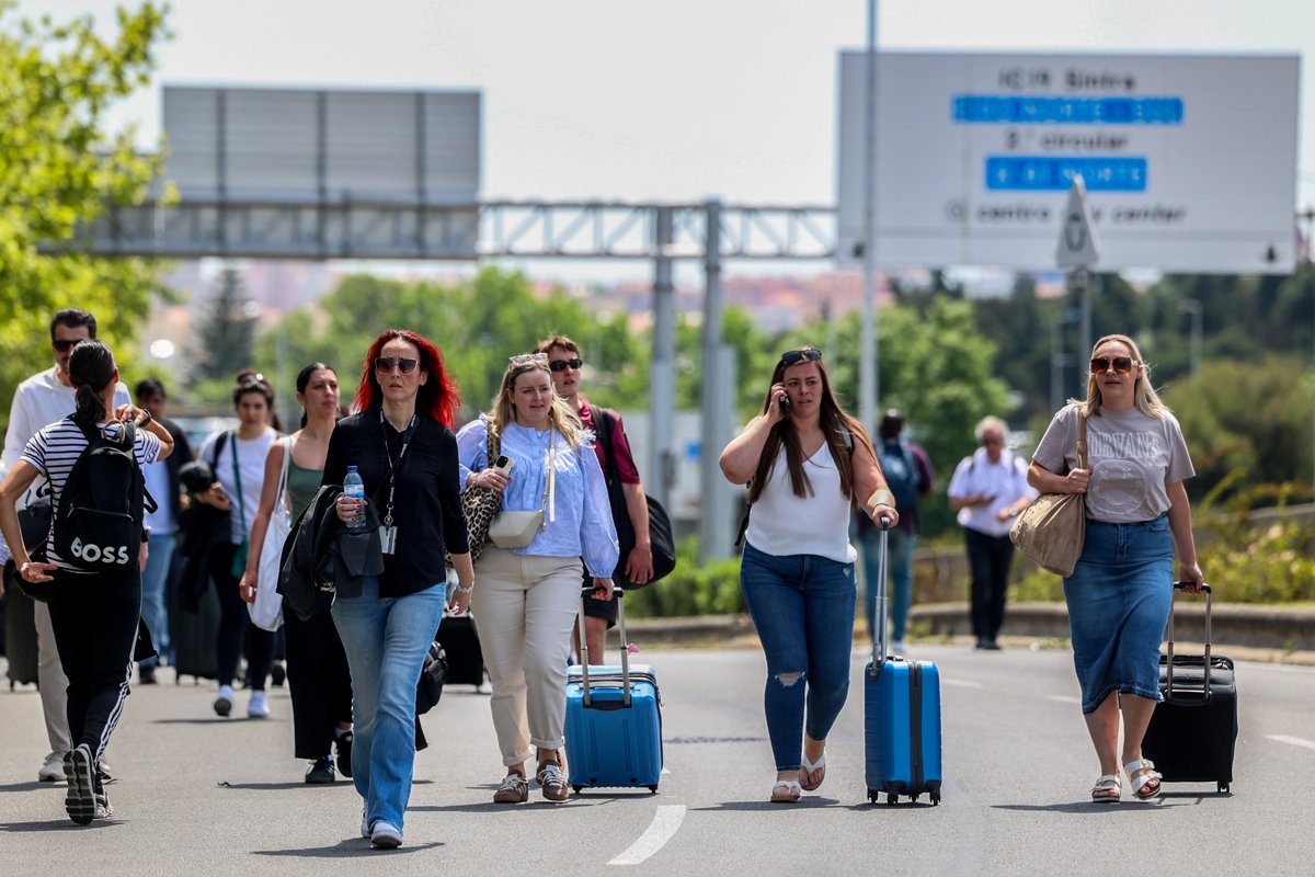 Пассажиры добираются пешком до зоны вылета в аэропорту Лиссабона во время блэкаута, 28 апреля 2025 года. Фото: Tiago Petinga / EPA
