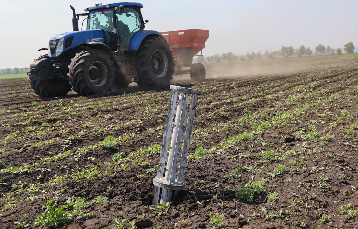 Трактор на фоне обломка снаряда на поле недалеко от Харькова, 8 мая 2022 года. Фото: Sergey Kozlov / EPA